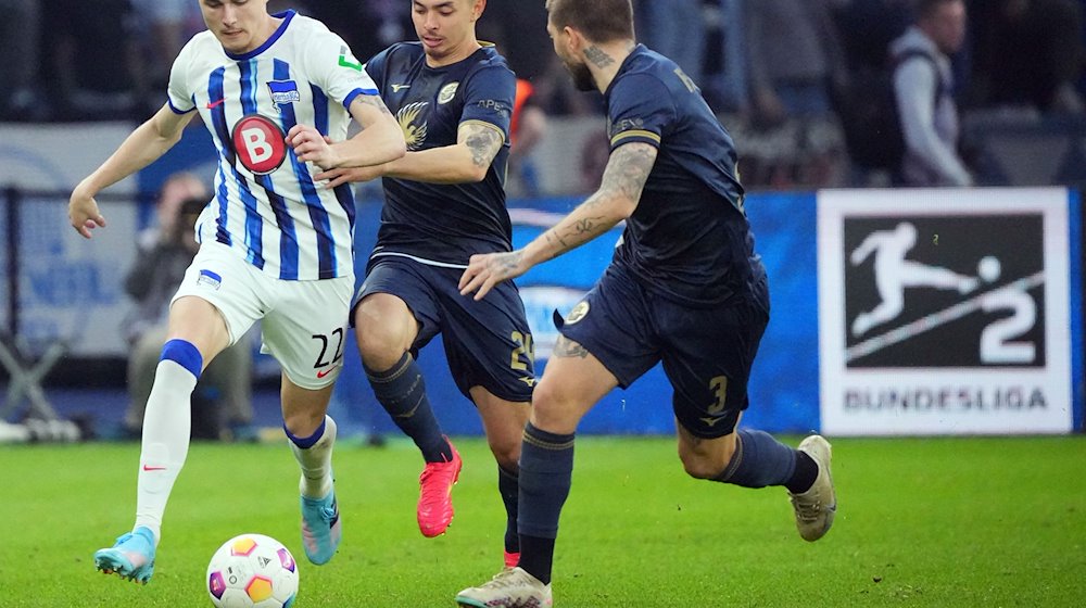 Herthas Palko Dardai (l) gegen John-Patrick Strauß (M) und Konstantinos Stafylidis (r) von Rostock. / Foto: Soeren Stache/dpa