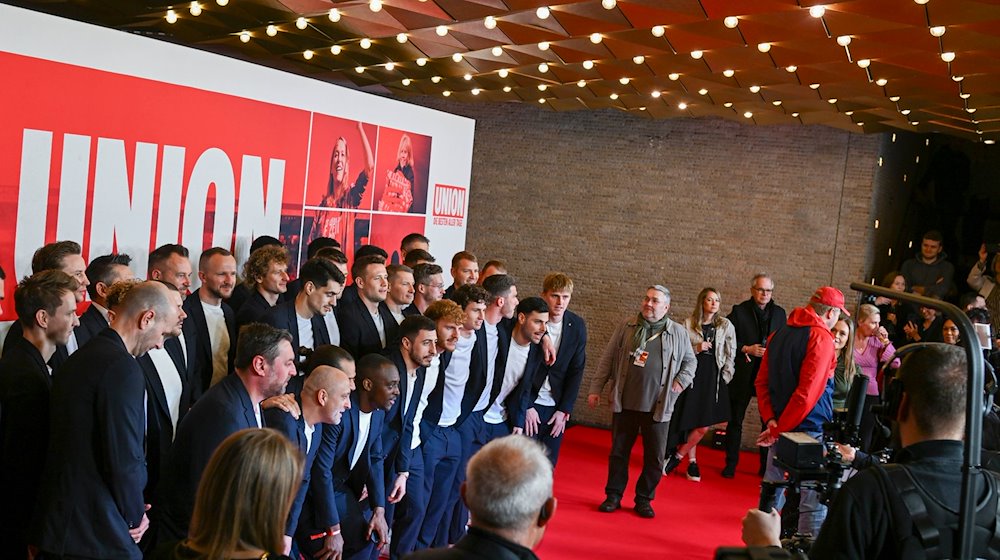 Der Cast und die Mannschaft von Union Berlin stehen bei der Filmpremiere auf dem roten Teppich im Kino International. / Foto: Jens Kalaene/dpa