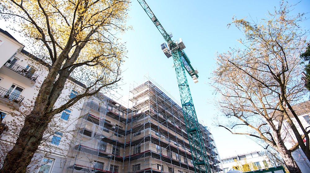 Ein Kran steht neben einem Neubau für ein Mehrfamilienhaus. / Foto: Daniel Bockwoldt/Deutsche Presse-Agentur GmbH/dpa/Symbolbild