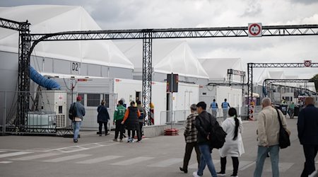 Bewohner und Mitarbeiter gehen im Ankunftszentrum am ehemaligen Flughafen Tegel in Richtung der Leichtbauhallen. / Foto: Sebastian Gollnow/dpa