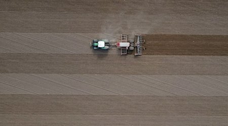 Ein Landwirt fährt mit seinem Traktor über ein Feld und bringt Saatgut in den Boden aus. / Foto: Patrick Pleul/dpa/Symbolbild