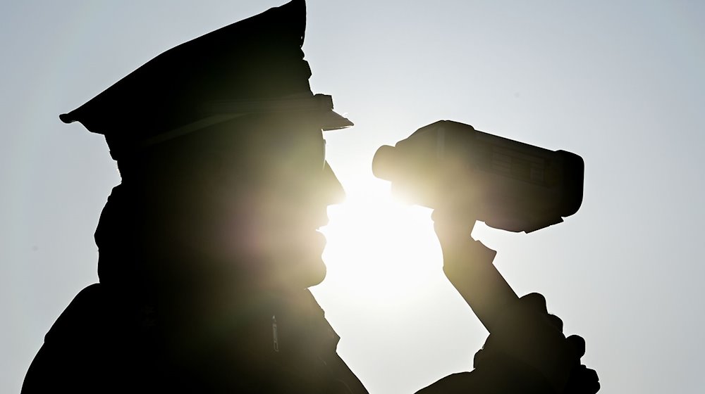 Ein Polizist kontrolliert mit einer Laserpistole Geschwindigkeiten. / Foto: Patrick Pleul/dpa-Zentralbild/dpa/Symbolbild