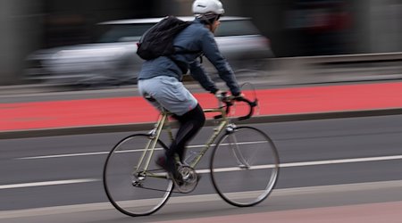 Ein Fahrradfahrer mit Helm fährt über einen Radweg an der Straße. / Foto: Monika Skolimowska/dpa-Zentralbild/dpa