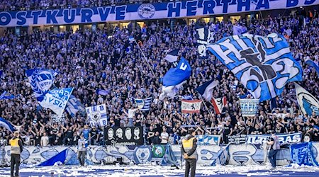 Fans von Hertha BSC feuern ihr Team aus der Ostkurve mit Fahnen an. / Foto: Andreas Gora/dpa