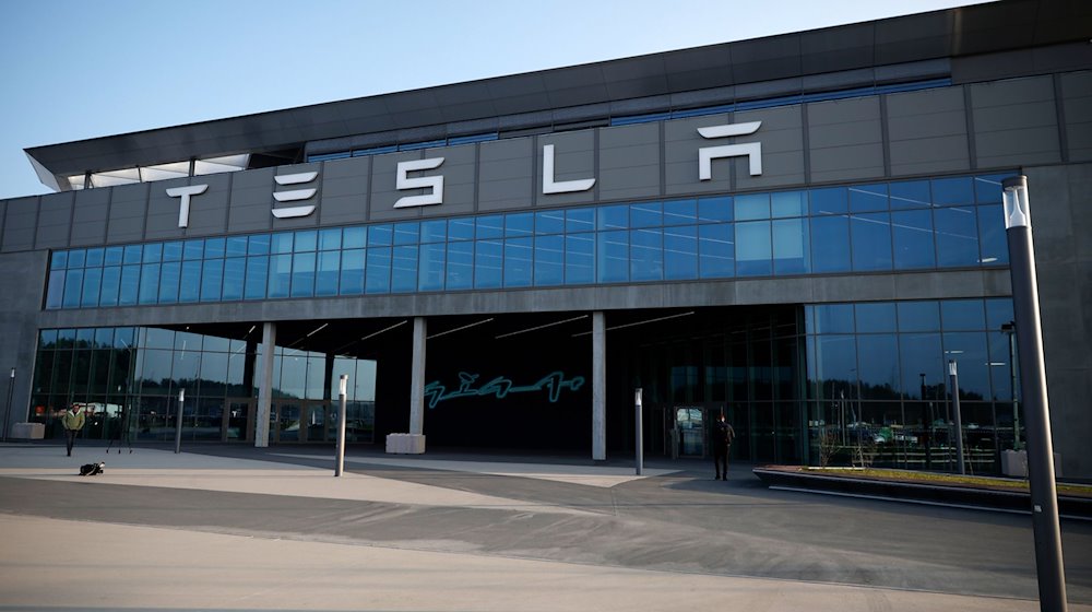 Die Morgensonne scheint auf den Eingang zum Tesla-Werk. / Foto: Carsten Koall/dpa