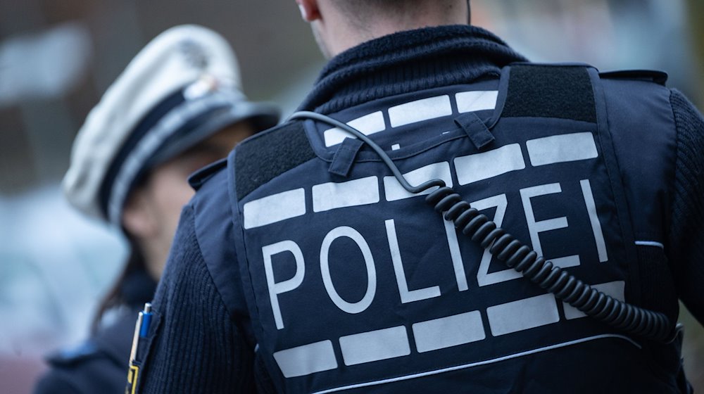 Eine Polizistin (l) und ein Polizist stehen an einer Straße. / Foto: Marijan Murat/dpa/Illustration