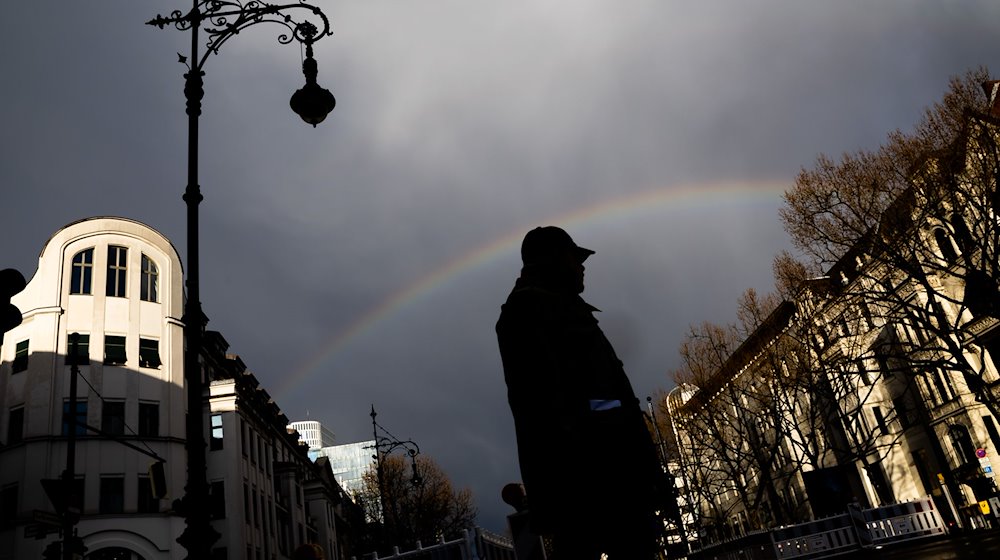 Ein Mann überquert unter einem Regenbogen den Kurfürstendamm. / Foto: Christoph Soeder/dpa/Archivbild