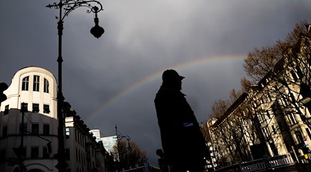 Ein Mann überquert unter einem Regenbogen den Kurfürstendamm. / Foto: Christoph Soeder/dpa/Archivbild