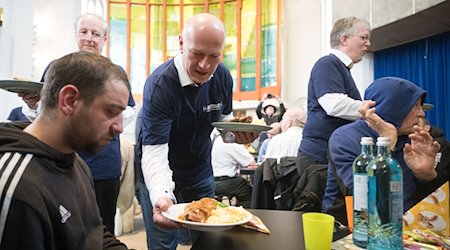 Kai Wegner (CDU, M), Regierender Bürgermeister von Berlin, serviert Essen während eines Osterbrunchs für Menschen ohne Wohnung. / Foto: Sebastian Christoph Gollnow/dpa