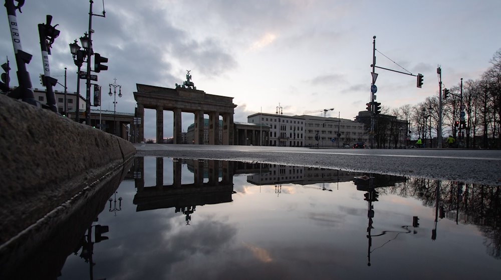 Das Brandenburger Tor spiegelt sich in einer Regenpfütze. / Foto: Paul Zinken/dpa-Zentralbild/dpa