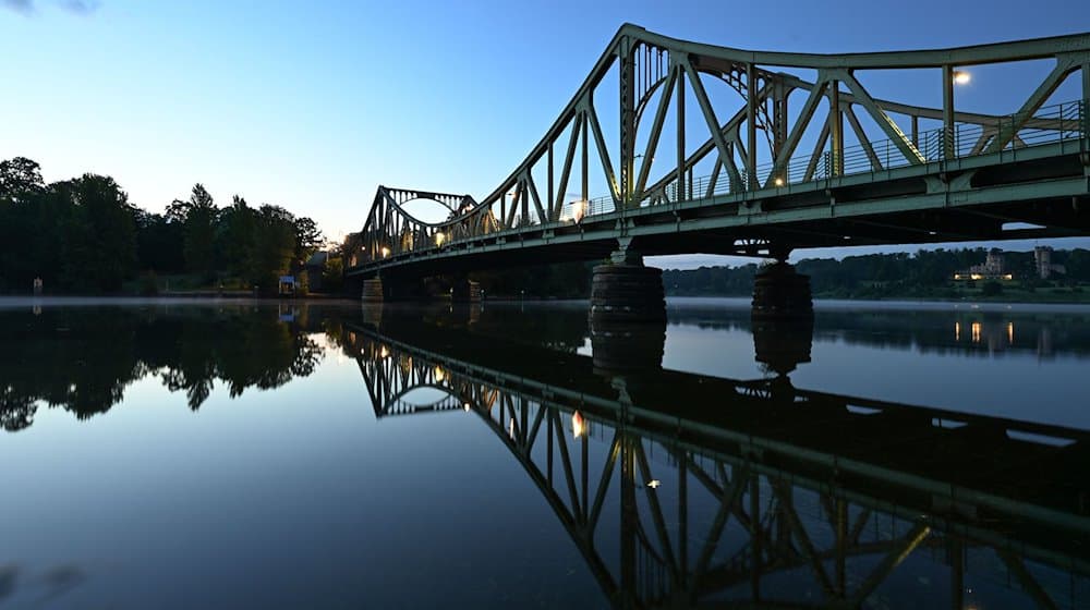 Die Glienicker Brücke spiegelt sich am Morgen im Wasser der Havel. / Foto: Soeren Stache/dpa