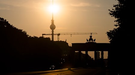 Das Brandenburger Tor und der Fernsehturm sind im Gegenlicht der aufgehenden Sonne zu sehen. / Foto: Christoph Soeder/dpa