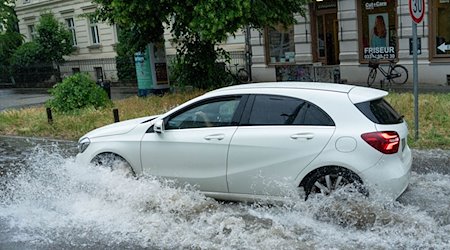 Ein Auto fährt durch der überflutete Geschwister-Scholl-Straße. / Foto: Georg Moritz/dpa