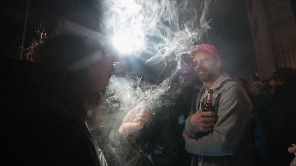 Teilnehmer rauchen während eines «Smoke In» vor dem Brandenburger Tor Cannabis. / Foto: Sebastian Gollnow/dpa