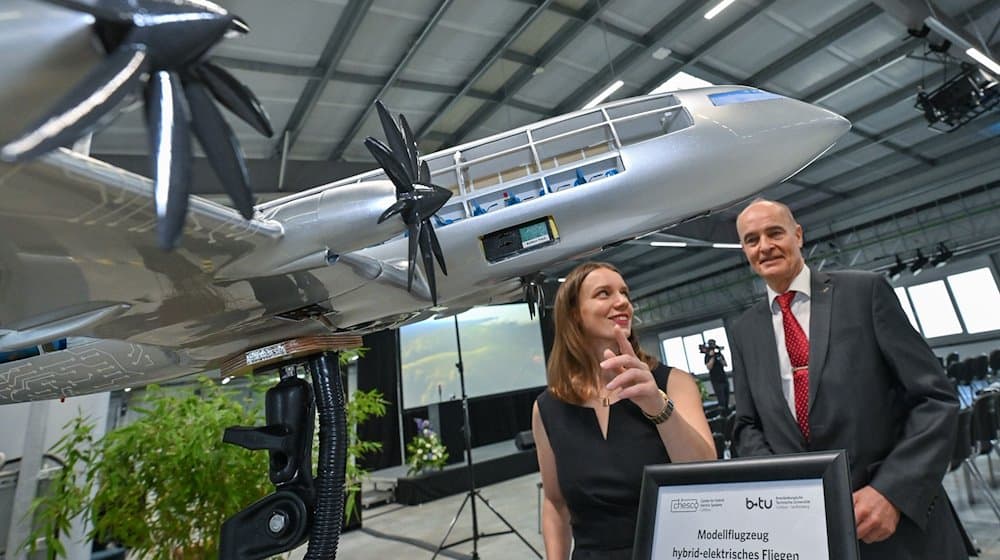 Jane Worlitz (l) und Professor Klaus Höschler stehen in der Forschungsfabrik hinter einem Modell eines hybrid-elektrischen Flugzeuges. / Foto: Patrick Pleul/dpa