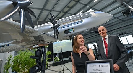 Jane Worlitz (l) und Professor Klaus Höschler stehen in der Forschungsfabrik hinter einem Modell eines hybrid-elektrischen Flugzeuges. / Foto: Patrick Pleul/dpa