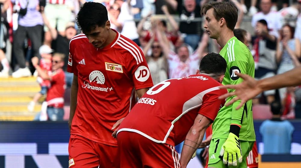 Berlins Diogo Leite (l-r), Robin Gosens und Torwart Frederik Rönnow stehen enttäuscht auf dem Platz. Union Berlin droht der Absturz in die 2. Bundesliga. / Foto: Federico Gambarini/dpa