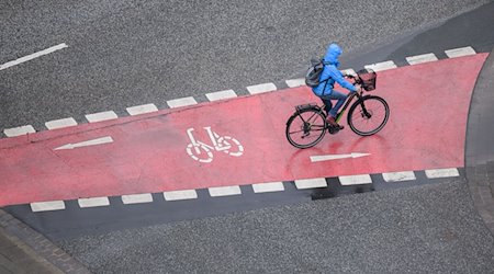 Eine Frau fährt bei Regen mit einem Fahrrad. / Foto: Julian Stratenschulte/dpa/Symbolbild