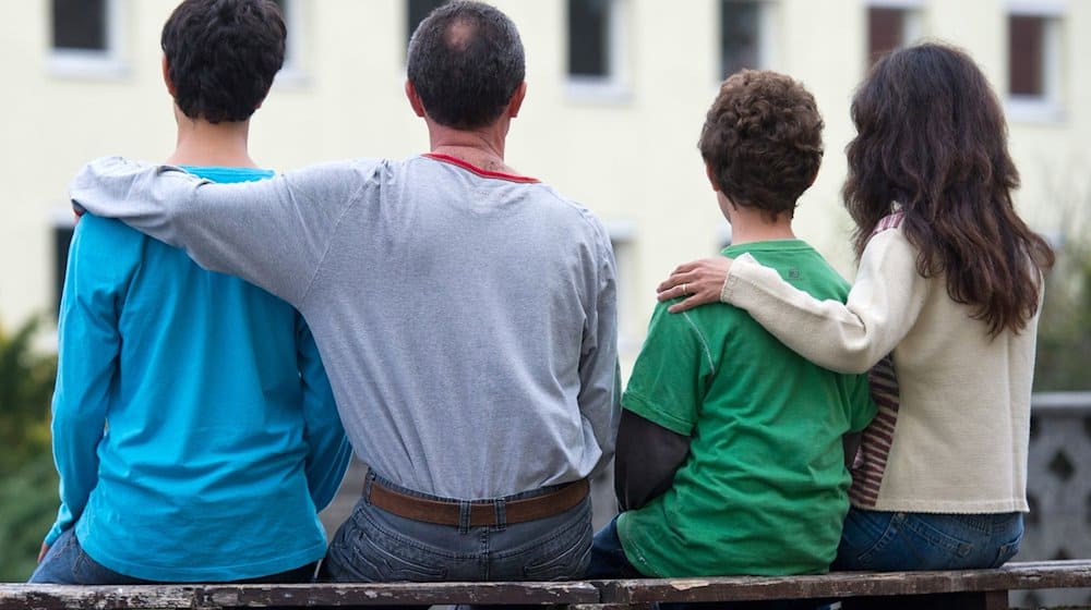 Eine syrische Familie sitzt vor einem Asylwohnheim der Zentralen Ausländerbehörde des Landes Brandenburg. / Foto: Patrick Pleul/zb/dpa/Archivbild