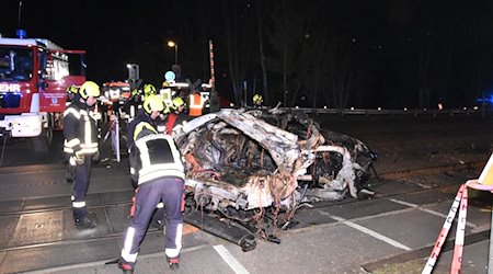 Rettungskräfte stehen am Wrack eines zerstörten Autos nach einem Unfall an einem Bahnübergang. / Foto: Christian Sappeck/BLP/dpa