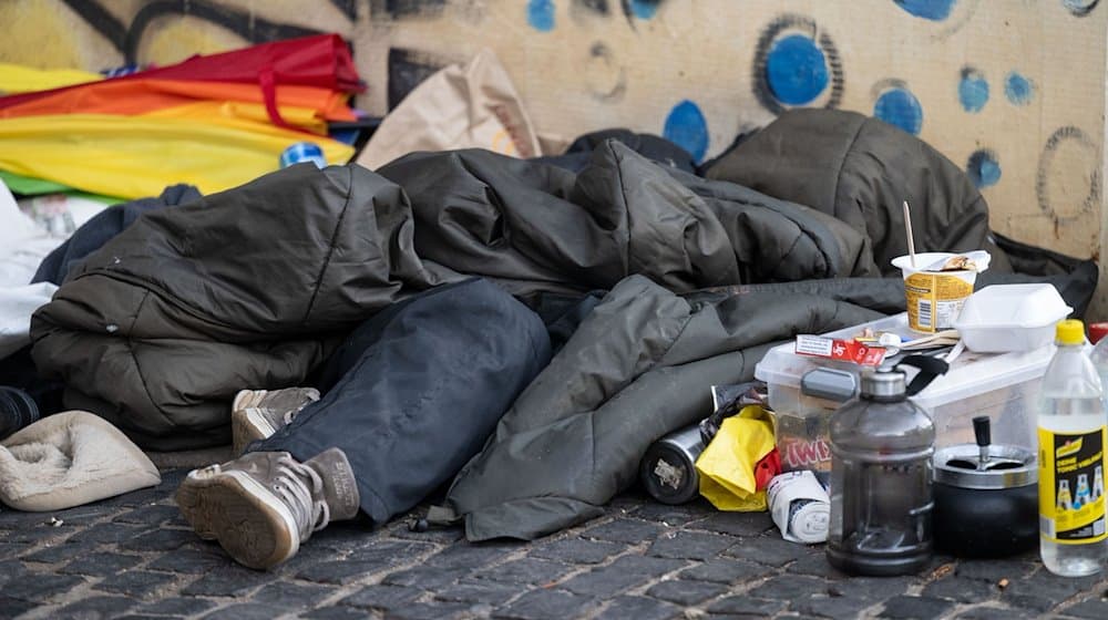 Eine Person liegt in der Innenstadt unter einem Schlafsack. / Foto: Marijan Murat/dpa/Archivbild