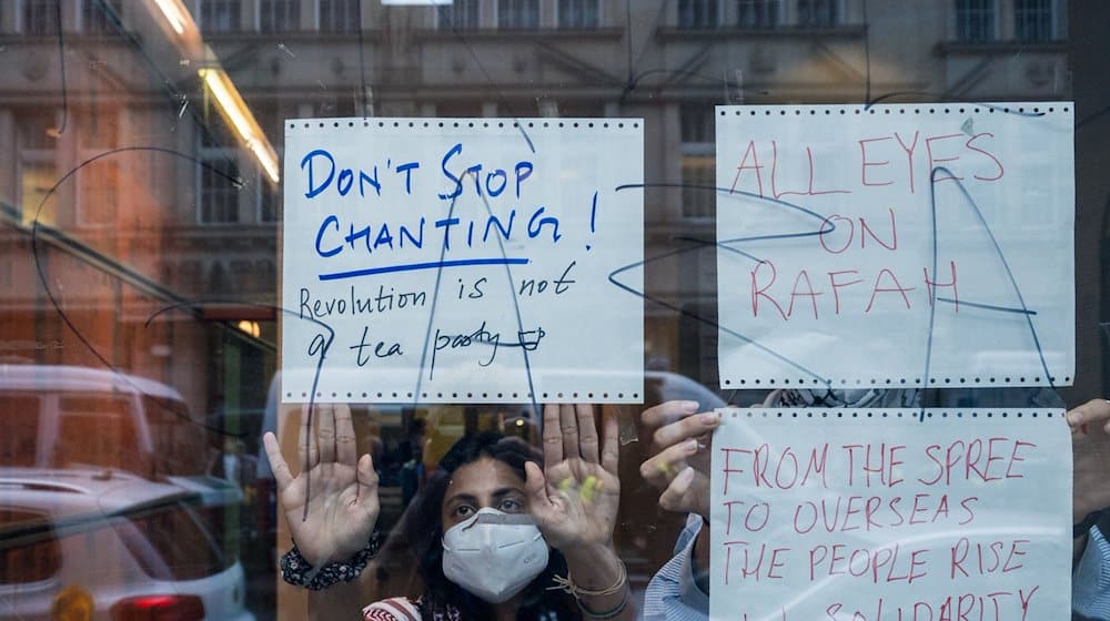 Pro-Palästinensische Demonstranten kleben im Institut für Sozialwissenschaften der Humboldt-Universität handgeschrieben Plakate von innen an die Scheibe. / Foto: Soeren Stache/dpa