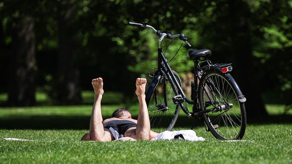 Ein Mann liegt auf einer Wiese und sonnt sich. Es wird sommerliches Wetter in Deutschland erwartet. / Foto: Hannes P. Albert/dpa