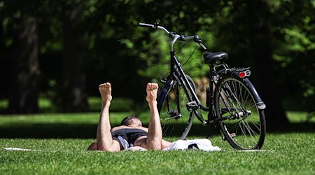 Ein Mann liegt auf einer Wiese und sonnt sich. Es wird sommerliches Wetter in Deutschland erwartet. / Foto: Hannes P. Albert/dpa