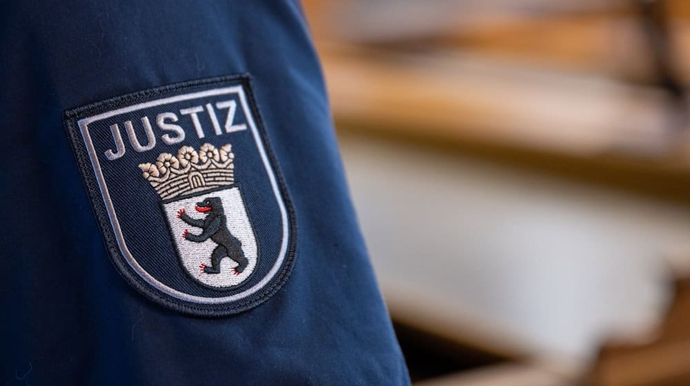 Ein Abzeichen mit dem Wort «Justiz» und dem Landeswappen von Berlin ist an der Uniform eines Justizvollzugsbeamten im Kriminalgericht Moabit angebracht. / Foto: Monika Skolimowska/dpa