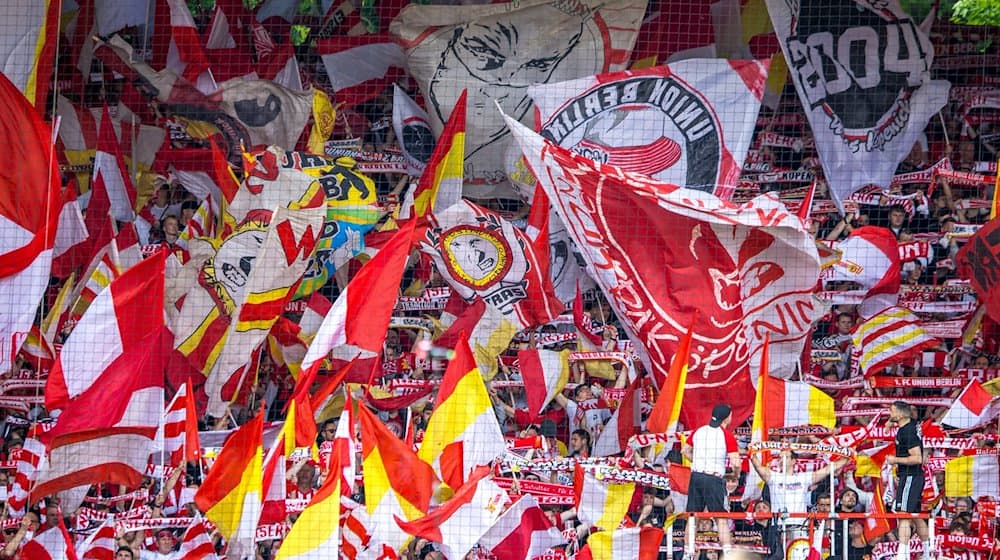 Fußball: Bundesliga, 1. FC Union Berlin - VfL Bochum, 32. Spieltag, An der Alten Försterei. Fans von Union Berlin feuern ihr Team mit Fahnen und Schals an. / Foto: Andreas Gora/dpa