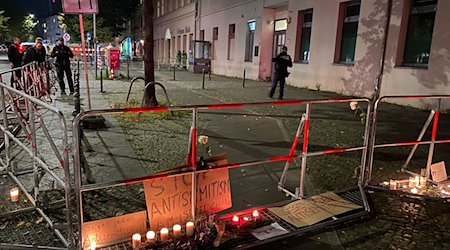 Brennende Kerzen stehen vor Schildern mit der Aufschrift «Stop Antisemitismus» an dem abgesperrten Bürgersteig. / Foto: Sascha Meyer/dpa
