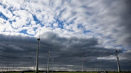 Windräder werden bei wolkigem Himmel kurzzeitig von der tiefstehenden Sonne beleuchtet. / Foto: Jens Kalaene/dpa