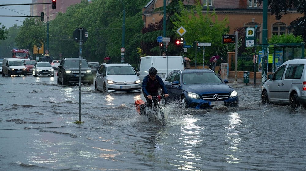 Ein Radfahrer und Autos fahren im Schritttempo durch die überflutete Zeppelinstraße. / Foto: Georg Moritz/dpa