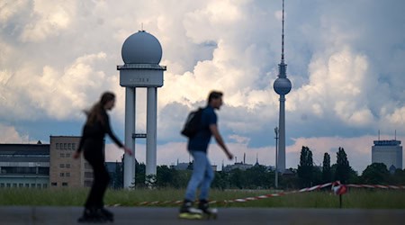 Zwei Inline-Skater fahren vor der Kulisse des Berliner Fernsehturms über das Tempelhofer Feld. / Foto: Monika Skolimowska/dpa