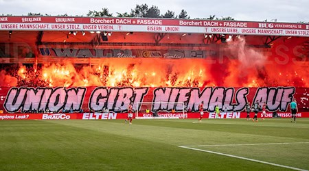 Fans von Union Berlin zünden Bengalisches Feuer auf der Waldseite hinter dem Schriftzug "Union gibt niemals auf!" Für das Abbrennen muss Union nun Strafe zahlen. / Foto: Andreas Gora/dpa