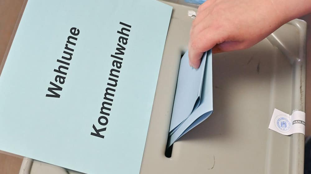 Eine Person steckt ihren Stimmzettel in eine Wahlurne mit der Aufschrift «Wahlurne Kommunalwahl». / Foto: Patrick Pleul/dpa