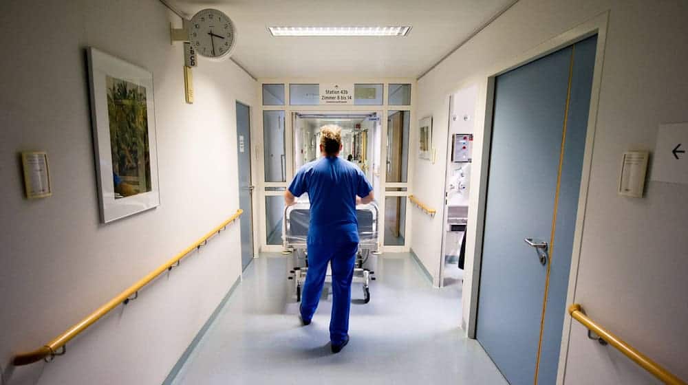 Ein Krankenpfleger schiebt in einer Klinik ein Krankenbett durch den Flur. / Foto: Daniel Bockwoldt/dpa