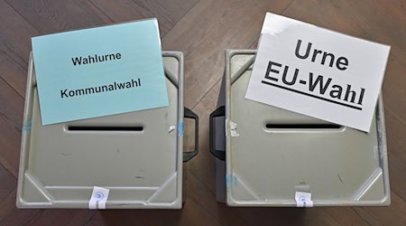 Zettel mit der Aufschrift «Wahlurne Kommunalwahl» (l) und «Urne EU-Wahl» liegen auf zwei Wahlurnen in einem Wahllokal. / Foto: Patrick Pleul/dpa