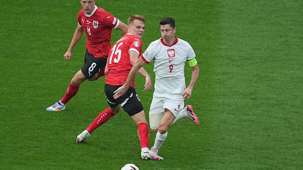 Polens Robert Lewandowski (r) am Ball gegen Österreichs Alexander Prass (l) und Österreichs Philipp Lienhart. / Foto: Michael Kappeler/dpa