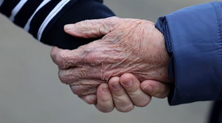 Eine Betreuungsassistentin hält die Hand von einer alten Frau. / Foto: Bernd Wüstneck/dpa