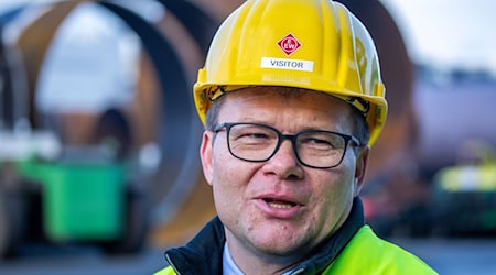 Carsten Schneider, Beauftragter der Bundesregierung für Ostdeutschland, beantwortet vor riesigen Metallrohren für die Fundamente von Off-Shore-Windkraftanlage im Großrohrwerk EEW Special Pipe Constructions im Seehafen die Fragen von Medienvertretern. / Foto: Jens Büttner/dpa