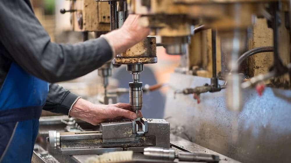 Ein Mitarbeiter bedient in der Produktionshalle eine Maschine zur Verarbeitung von Metall. / Foto: Monika Skolimowska/dpa-Zentralbild/dpa/Symbolbild