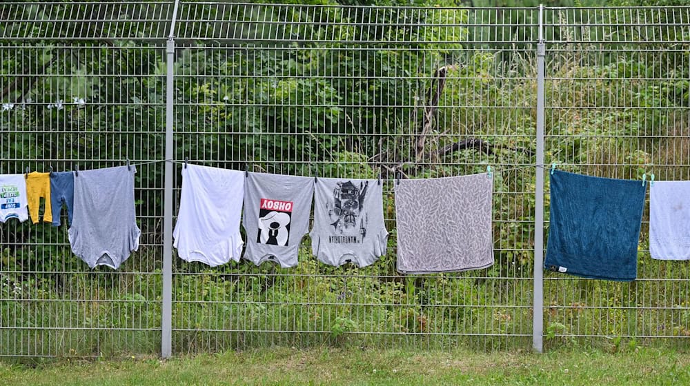 Wäsche von Migranten hängt zum trocknen am Zaun der Zentralen Erstaufnahmeeinrichtung für Asylbewerber (ZABH) des Landes Brandenburg. / Foto: Patrick Pleul/dpa