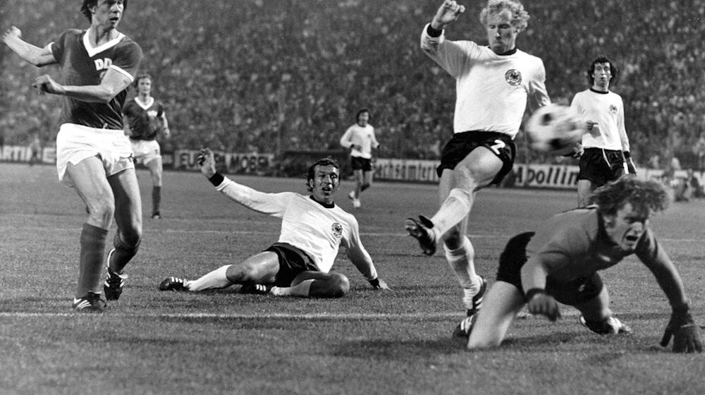 Der Höhepunkt des «Dramas» vom 22.06.1974 im Hamburger Volksparkstadion ist erreicht - auf den Knien blickt Sepp Maier fassungslos dem Ball hinterher, der zum 1:0-Sieg für die DDR ins bundesdeutsche Netz fliegt - getreten von Jürgen Sparwasser (l.). / Foto: Roland Witschel/dpa