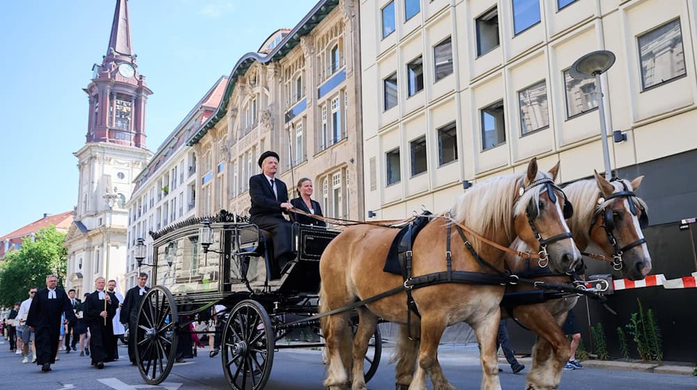 Eine Prozession, in der Kinder und Erwachsene die Gebeine der ersten mittelalterlichen und frühneuzeitlichen Berlinerinnen und Berliner in kleinen Särgen von der Parochialkirche zum Petriplatz tragen, wird von einer Kutsche und Geistlichen angeführt. / Foto: Annette Riedl/dpa