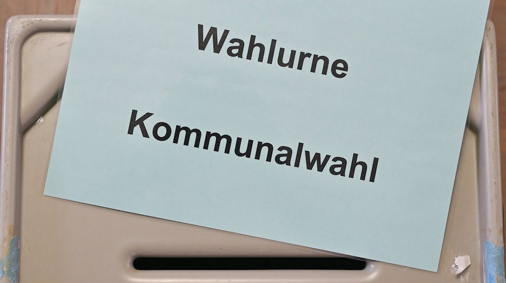 Ein Zettel mit der Aufschrift «Wahlurne Kommunalwahl» liegt auf einer Wahlurne in einem Wahllokal. / Foto: Patrick Pleul/dpa