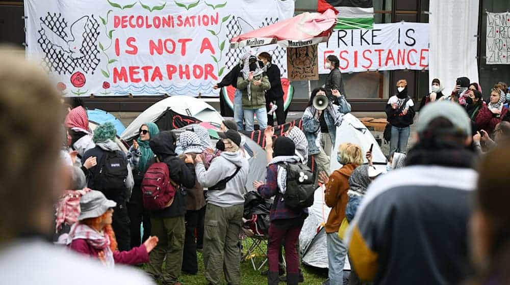 Teilnehmer stehen während einer pro-palästinensischen Demonstration der Gruppe «Student Coalition Berlin» auf dem Theaterhof der Freien Universität Berlin. Die Teilnehmer haben am Dienstagvormittag den Platz mit Zelten besetzt. / Foto: Sebastian Gollnow/dpa