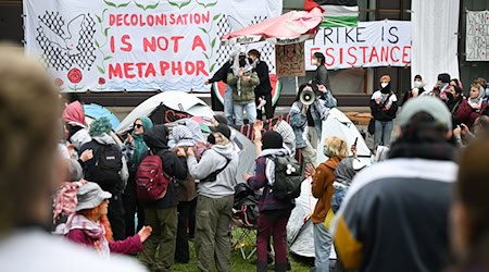 Teilnehmer stehen während einer pro-palästinensischen Demonstration der Gruppe «Student Coalition Berlin» auf dem Theaterhof der Freien Universität Berlin. Die Teilnehmer haben am Dienstagvormittag den Platz mit Zelten besetzt. / Foto: Sebastian Gollnow/dpa