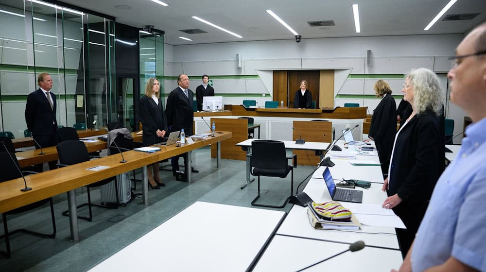 Die Vorsitzende Richterin Barbara Lüders (M) und die Verfahrensbeteiligten stehen im Gerichtssaal. / Foto: Bernd von Jutrczenka/dpa/Archivbild