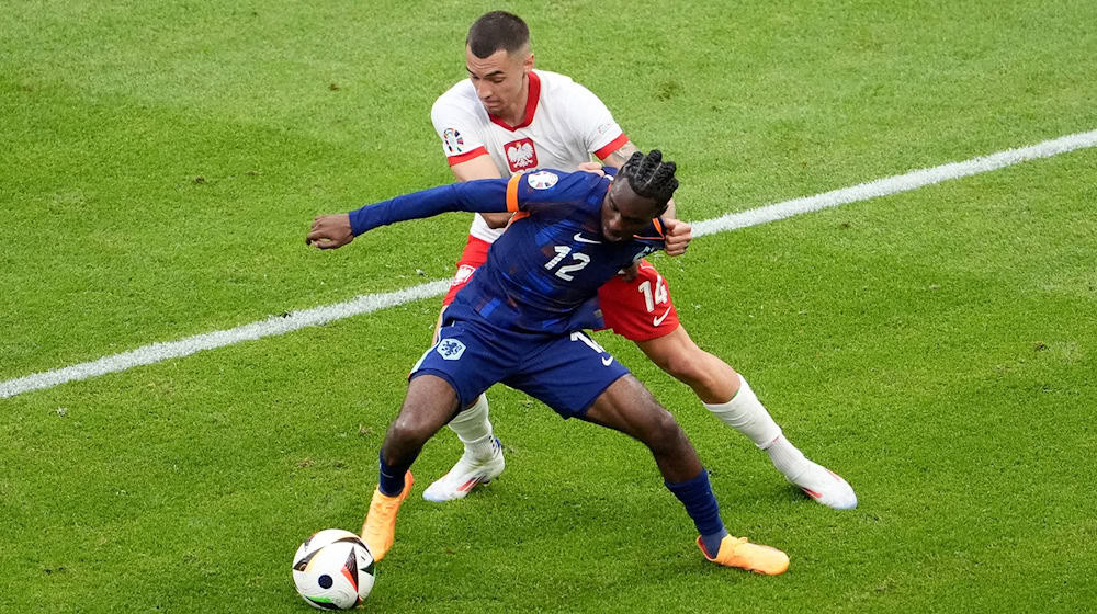 Jeremie Frimpong von den Niederlanden (vorn) und Polens Jakub Kiwior kämpfen um den Ball. / Foto: Marcus Brandt/dpa